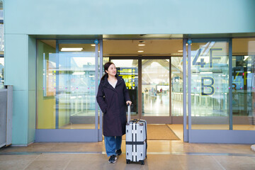 Asian woman with suitcase at airport terminal entrance