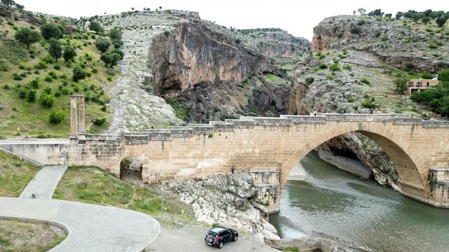 Aerial drone view of Malabadi Bridge, a historic stone arch bridge crossing the Batman River in southeastern Turkey, surrounded by rocky canyon landscapes in the Mesopotamia region
