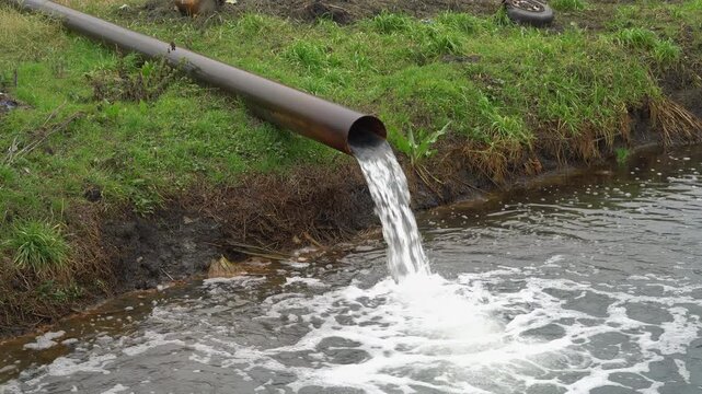 Wastewater discharge from industrial pipe into polluted canal, murky contaminated water flowing into the waterway representing environmental damage and ecological hazard.