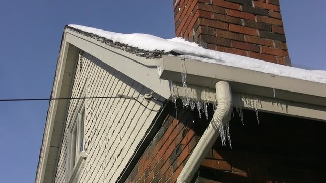 Frozen eavestrough with downspout and icicles. Wide angle. HD video. 