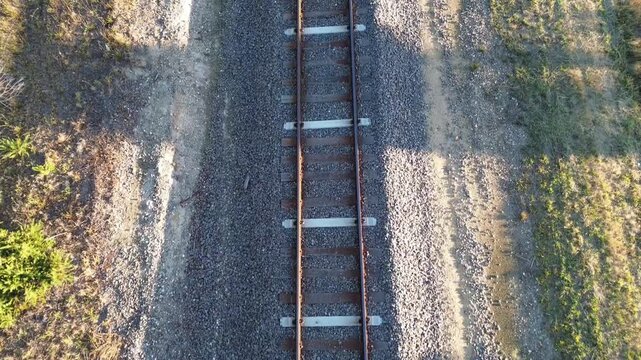 Top down aerial view of railway tracks running through rural landscape