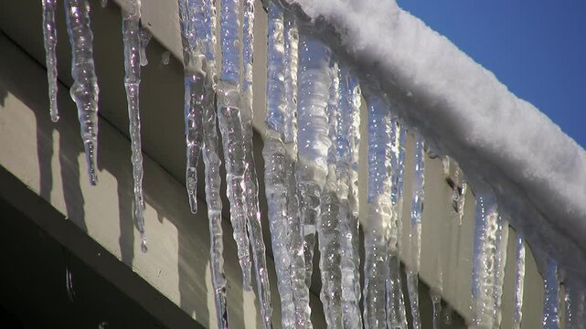 Frozen eavestrough with icicles. Detail of dripping water. HD video. 