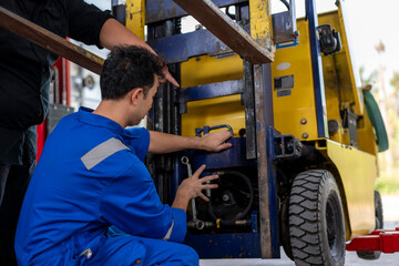 Mechanics repairing forklift engine in vehicle workshop