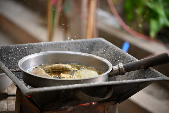 Hot oil splashing while frying traditional Mexican antojitos on a coal brazier, Molotes