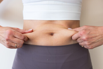 Naklejka premium Woman in activewear pinching her abdomen to show body fat