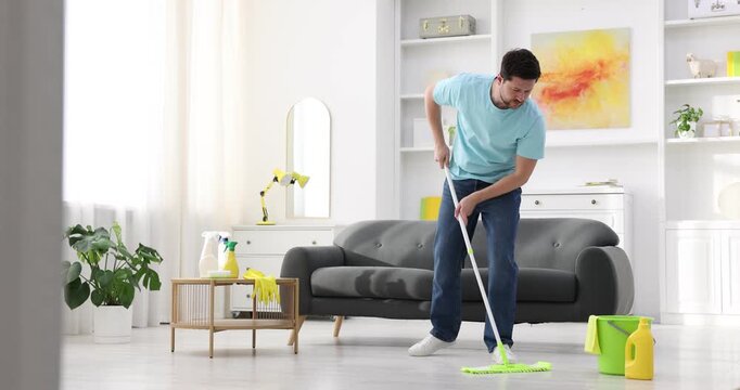 Spring cleaning. Man tidying up floor with mop at home
