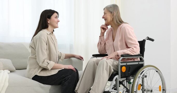 Woman in wheelchair talking with her caretaker at home