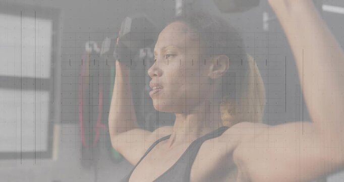 Woman performing overhead dumbbell press in gym, initiating rep by lowering for shoulder strength