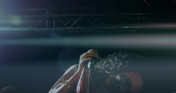 Music vocalist starting note, gripping mic, singing and whipping hair under lights showing emotion