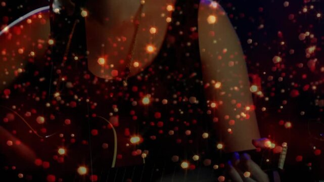 Camera pulling back, performer moving guitar toward mic, singing music with gold overlay particles