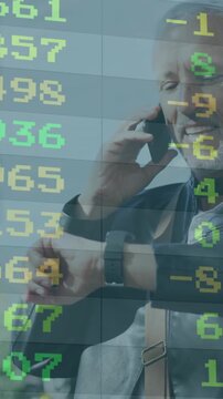 Vertical video: Senior exec taking call after market alert, checking watch while stocks scroll