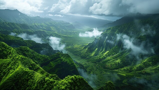 Aerial view of a dramatic, verdant valley with steep mountains, mist, and cloudy sky