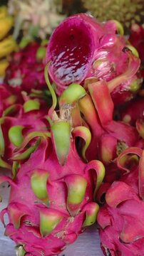 Vertical screen Pink Dragon Fruit And Bananas Vietnam Vibrant Stall Closeup Showing Speckled Flesh And Curved Yellow Bunches, Sliced Pitaya Reveal White Dotted Pulp, Tropical Vendor Display