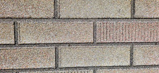 Wall texture with rough gray and reddish bricks creating a patterned surface © FlorianSchultze