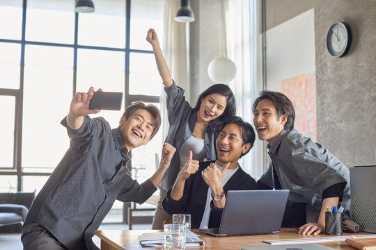 A group of cheerful office coworkers snapping a selfie