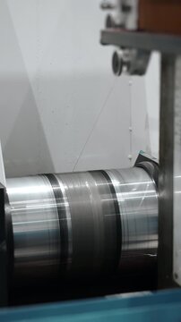 Wire EDM machine cutting rotating metal cylinder with thin wire electrode during precision electrical discharge machining in industrial workshop.