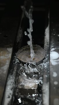 Wire EDM machine cutting metal part with thin wire electrode and coolant fluid during precision electrical discharge machining.