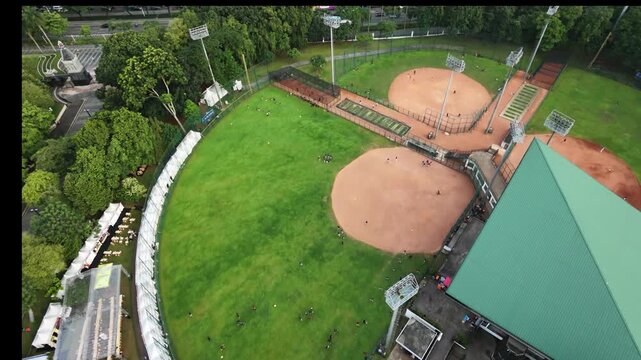 Cinematic top-down aerial view of a professional softball diamond in urban area.