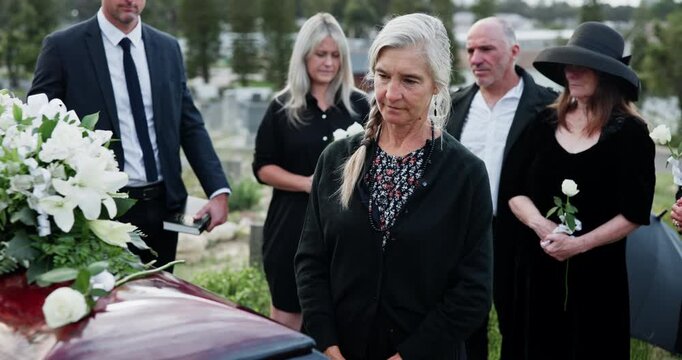 Sad, old woman and rose with casket at funeral ceremony, burial service and mourning loss. Senior person, flower and rest in peace, emotional breakdown and tribute gathering at farewell memorial