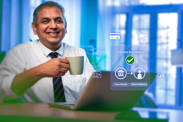 Obraz premium Indian mid age handsome businessman doing online digital payment successful on laptop at office desk