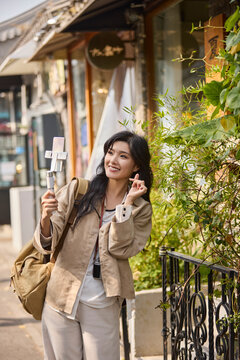 Happy female influencer webcasts while traveling
