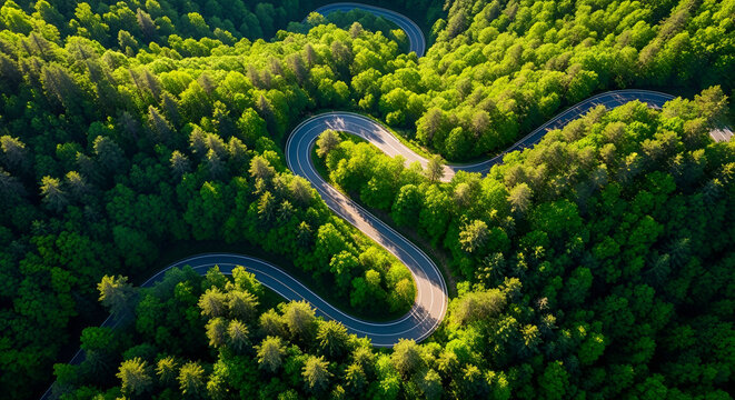 Aerial drone view of a winding mountain road in a lush green forest with sharp turns and vibrant trees
