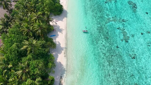 Drone flying along the scenic coastline of Thoddoo Island, revealing a perfect combination of white sandy shores and azure Indian Ocean.