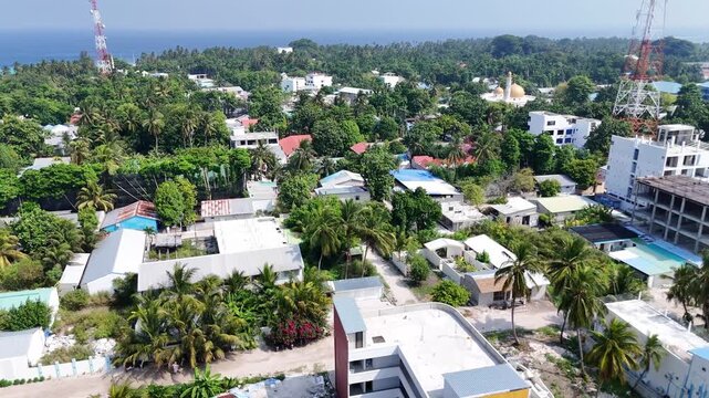 High-angle drone perspective showing the harmony between tropical nature and human settlement on the inhabited island of Thoddoo.