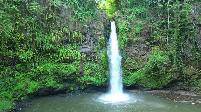 Aerial view flying backwards with the water flowing between the rocks of the beautiful Gugue waterfall in the background.S&atilde;o Tom&eacute;,Africa