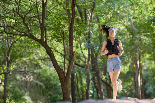Young woman jogging along a path surrounded by lush trees