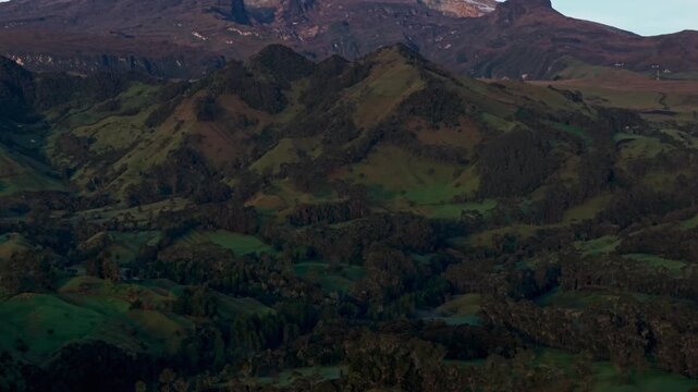 Aerial view revealing the snow capped nevado del ruiz volcano behind the green andean mountains
