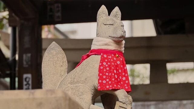Silent stone fox figure wearing red bib on shrine steps