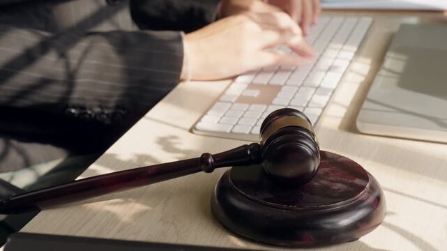 Judge gavel on office desk beside computer keyboard representing digital law and legal technology. Justice system, legal authority and modern law office concept.
