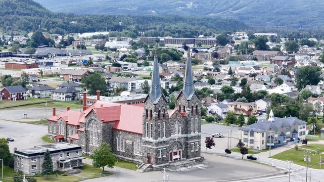 Aerial view of St Ann Catholic Church near Sainte Anne des Monts in Quebec town with houses and mountains. g.