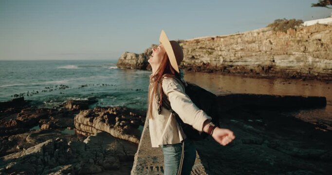 Woman, happy and open arms with travel for ocean view, backpack and excited for vacation in summer. Person, smile and freedom with energy, bag and perspective for memory on tourism holiday at seaside