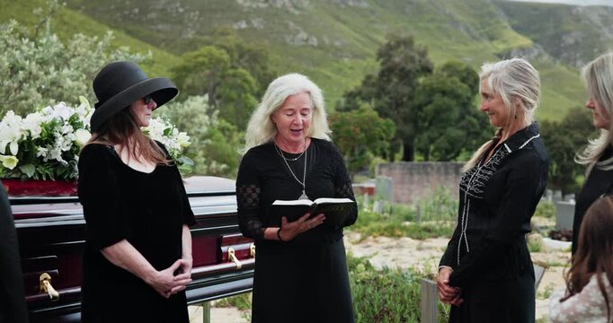 Officiant, family and reading bible for funeral at cemetery, graveyard or outdoor for farewell. Mature, people or group together for grief, death and respect or support for eulogy, book and pastor