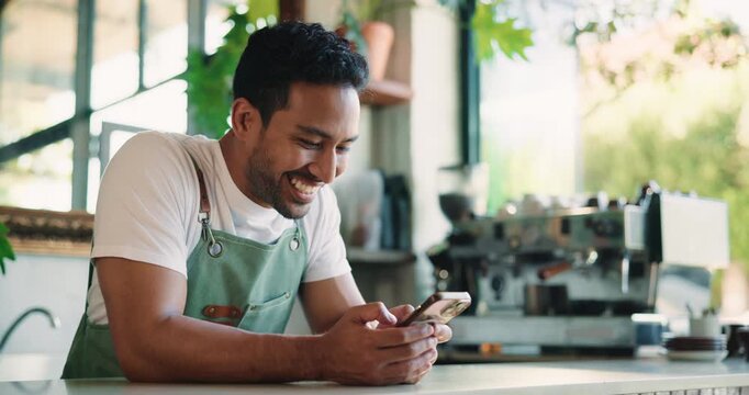 Barista, man and break in coffee shop with phone, social media and notification for text message. Happy, person and worker in cafe with tech, mobile app and browsing website for hospitality trends.
