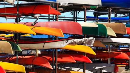 Naklejka premium Kayaks and canoes stored on a rack near water