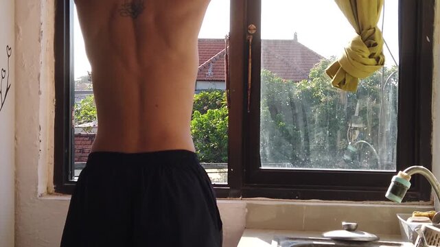 Man stretching spine and upper back in natural morning sunlight, healthy body movement