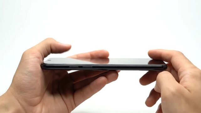 Holding smartphone with side view.
