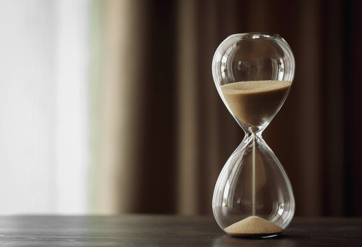 An hourglass sits on a wooden table. concept of urgent planning, time management, and quick decision making. with copy space
