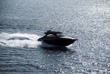Fototapeta premium A speedboat is moving across the water. It’s a calm, blue ocean scene.