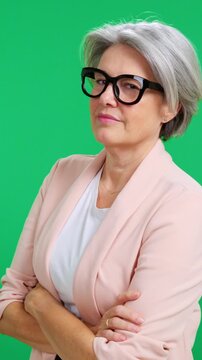 Confident senior businesswoman crossing arms on green screen
