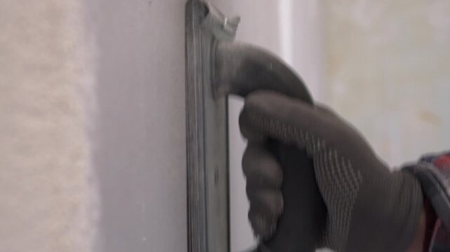 worker using emery tool sanding a plaster wall surface