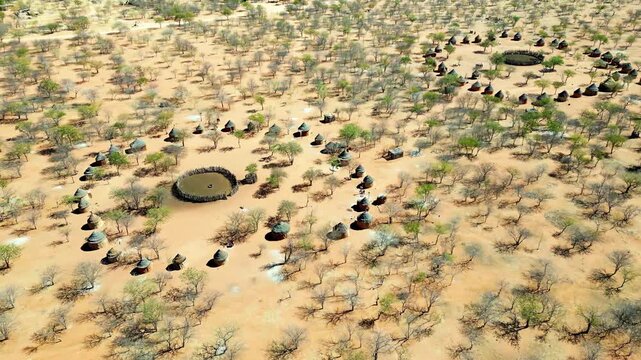Aerial drone view of a traditional circular Himba village settlement in northern Namibia with huts arranged around a central livestock enclosure