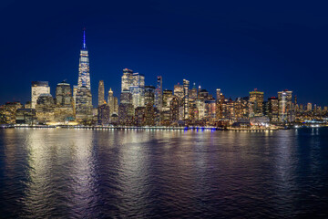 Obraz premium New York skyline at night. NYC night metropolis skyline view. New York as a big American city. New York City glowing at night. Manhattan skyline at night. Lower Manhattan aerial skyline view.