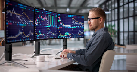 Young Professional Monitoring Financial Markets On Multiple Screens