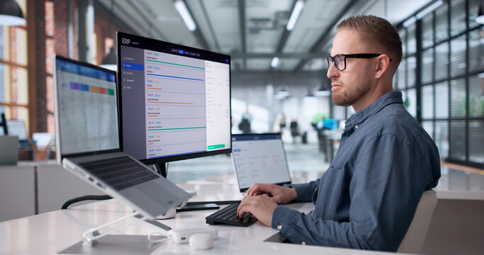 Young Professional Managing Cloud-Based ERP Software On Laptop