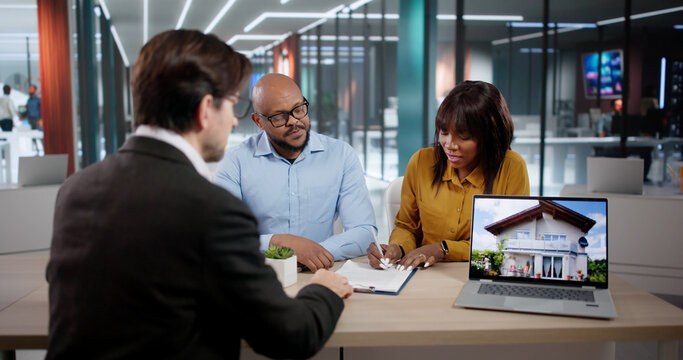 Young Couple Signing A Contract With Real Estate Agent
