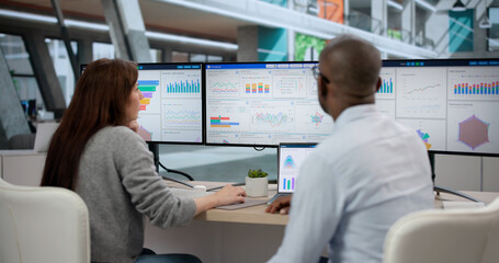 Young African Man And Woman Analyze Data On Multiple Screens